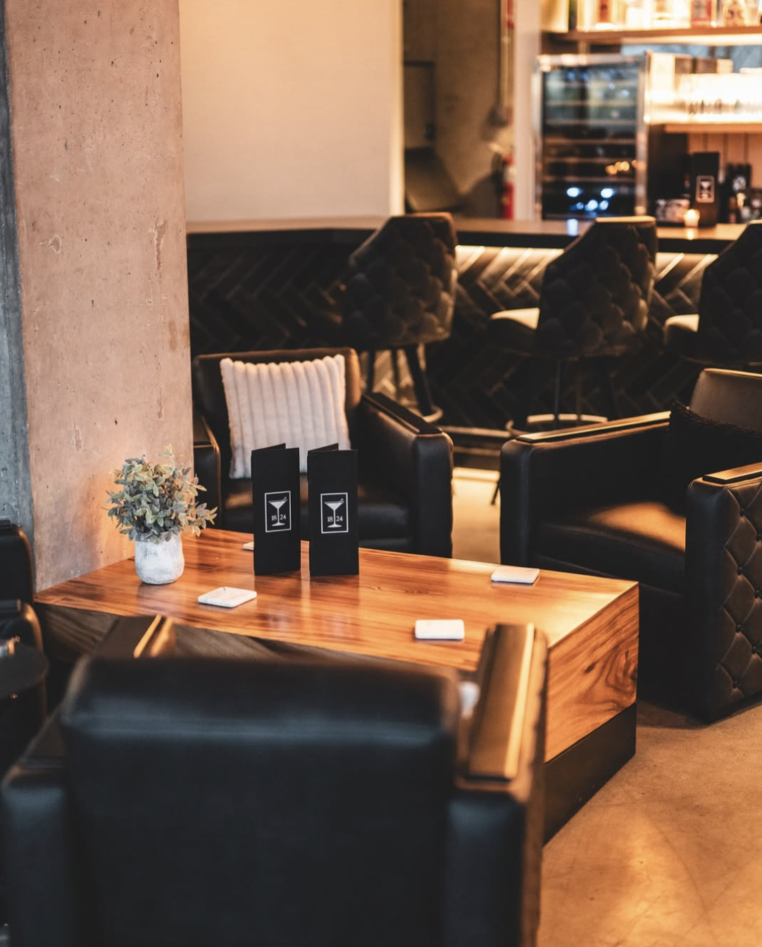 Walnut lounge table with 1824 menus, a small plant, and tufted leather chairs