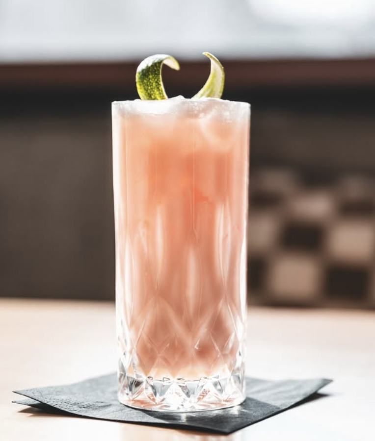 Crystal-cut highball with a blush pink cocktail and a twisted lime garnish